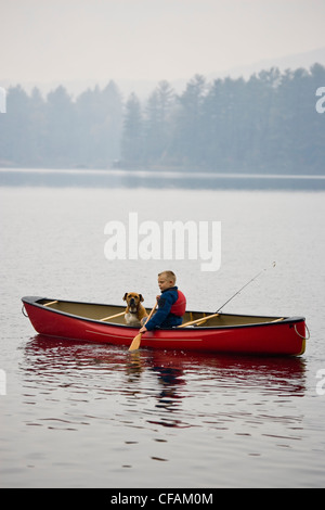 Junge Angeln mit Hund im Kanu auf Quelle See, Algonquin Provincial Park, Ontario, Kanada. Stockfoto