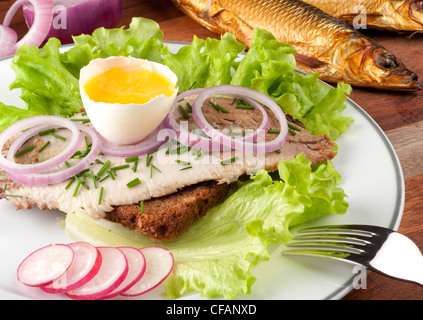 Dänischen Smorrebrod - Sol über Gudhjem oder Sonne über Gudhjem. Geräucherten Hering auf Roggenbrot mit Eigelb, Radieschen und Schnittlauch Stockfoto