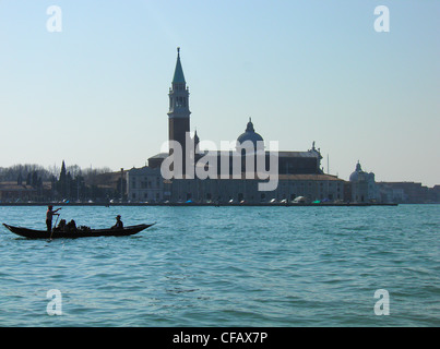 Ein Gondoliere, stehend auf einer Gondel führt Touristen vor San Marco, Venedig Stockfoto