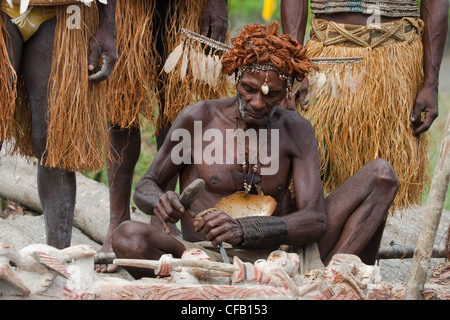 Mann vom Stamm Asmat schnitzen mit einem Meißel, Agats Dorf, Neu-Guinea, Indonesien Stockfoto