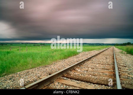 Railroad tracks mit Wolken im Hintergrund in der Nähe von Didsbury, Alberta, Kanada Stockfoto