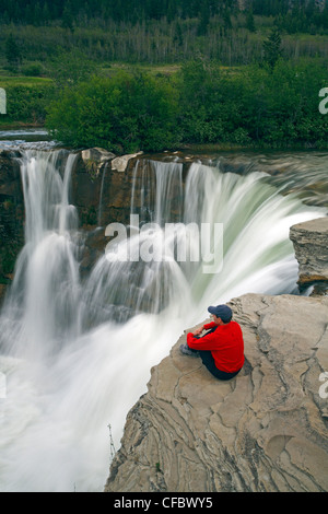 Mann sitzt neben Lundbreck Falls, Alberta, Kanada Stockfoto