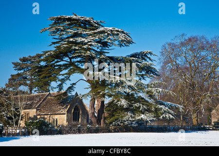 Verschneite Blick auf St. Peter Kirche eine typische Landkirche in Cotswold Dorf Ampney St Peter, Gloucestershire, England, UK Stockfoto