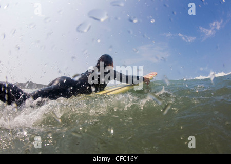 Eine weibliche Surfer paddeln Cox Bay Stockfoto