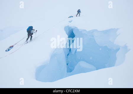 Zwei Skifahrer auf eine ausgedehnte Ski-Traverse überqueren eine klaffende Gletscherspalte im abgelegenen Darwin Range, Südchile Stockfoto