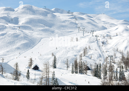 Vogel-Skigebiet in den Julischen Alpen in Slowenien, zeigt eine Sesselbahn, Skifahrer und Hänge mit Spuren im Schnee Stockfoto