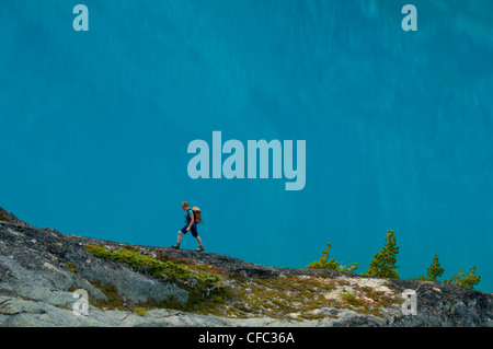 Eine junge Frau Wanderungen vor einem blauen See der Niut Range, British Columbia, Kanada Stockfoto