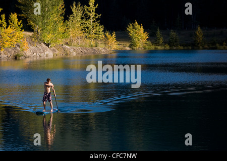 Ein junger Mann Paddleboards am Steinbruch-See in Canmore, AB Stockfoto