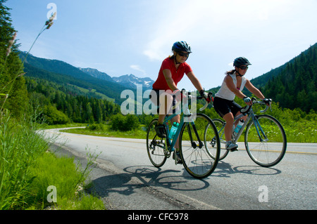 Zwei junge Frauen auf ihre Rennräder Radsport nehmen Sie die landschaftlich schöne Strecke von Kaslo nach New Denver, British Columbia, Kanada Stockfoto