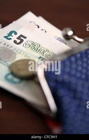 Sterling-Banknoten und-Münzen ticken aus einem offenen Damenportemonnaie Stockfoto
