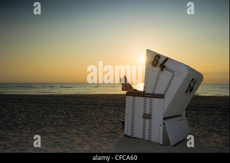 Frau zum Entspannen in überdachten Strandkorb im Sonnenuntergang, Westerland, Sylt, Schleswig-Holstein, Deutschland Stockfoto