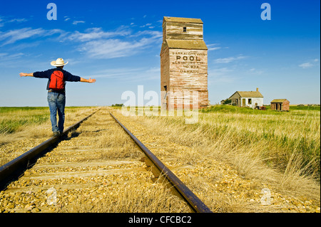 ein Mann Wanderungen entlang der Bahnstrecke mit verlassenen Aufzüge im Hintergrund, Dankin, Saskatchewan, Kanada Stockfoto