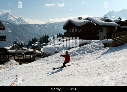 Skifahrer auf der Piste an einem sonnigen Tag mit Skiort Courchevel 1850 im Hintergrund Stockfoto