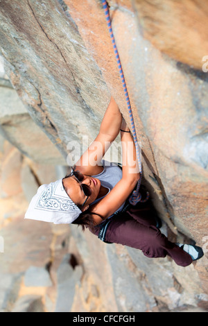 Overhead Schuss ein asiatisch-amerikanische, weibliche Kletterer auf eine Mauer aus Granit. Stockfoto
