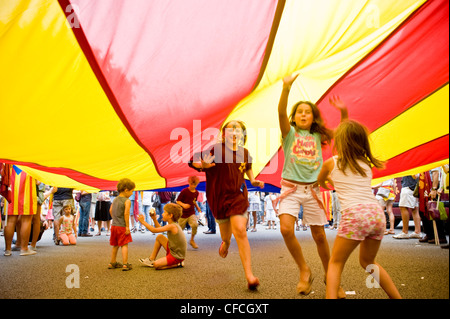 Kinder spielen und genießen Sie unter einer großen katalanischen Flagge während der katalanischen Nationalfeiertag in Barcelona. Stockfoto