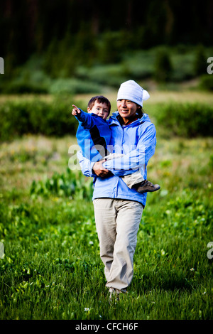 Eine Frau geht durch eine Wiese am Squaw Pass halten ihr 2 Jahre alten Sohn. Stockfoto