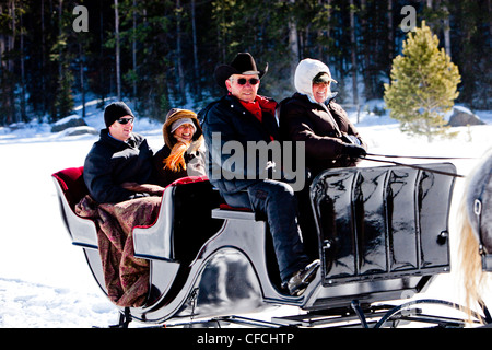 Freunde sitzen unter Decken im Winter, auf Schnee gefüllte Schlittenfahrt. Stockfoto