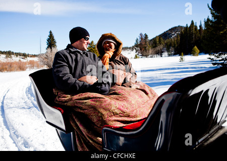 Freunde sitzen unter Decken im Winter, auf Schnee gefüllte Schlittenfahrt. Stockfoto