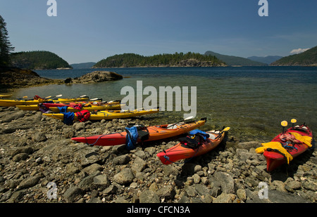 Leeren Kajaks liegen entlang der Küstenlinie von Desolation Sound hochgezogen. Desolation Sound, British Columbia, Kanada. Stockfoto