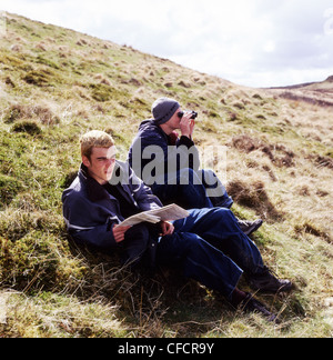 Junge Wanderer Männer suchen an der Karte und Umgang mit Fernglas suchen ihre Position auf einem walisischen Hügel in Carmarthenshire Wales UK KATHY DEWITT Stockfoto