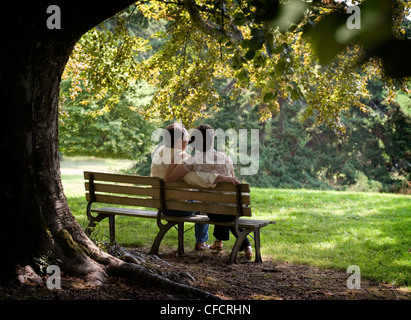 Ein paar auf Bank sitzend Stockfoto