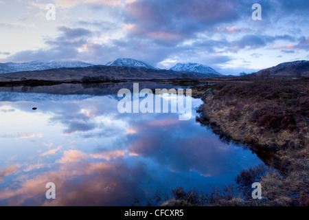 Dawn Blick auf Loch Ba spiegelt den Himmel und Ferne schneebedeckte Berge, Rannoch Moor, Highland, Schottland, Vereinigtes Königreich Stockfoto