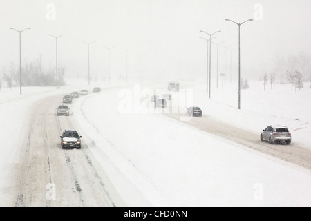 Verkehr auf einer schneebedeckten Straße während eines Schneesturms Winter. Winnipeg, Manitoba, Kanada. Stockfoto