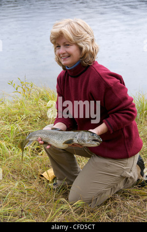 Frau mittleren Alters mit fangfrischen Seeforelle, Yukon Territorium, Kanada. Stockfoto