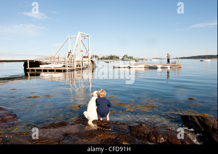 ein Junge und sein Hund beobachten Fischer angeln aus dem dock Stockfoto