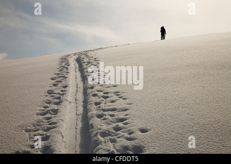 Eine Silhouette des weiblichen Backcountry Skifahrer entlang einer Spur im Schnee Häuten. Stockfoto