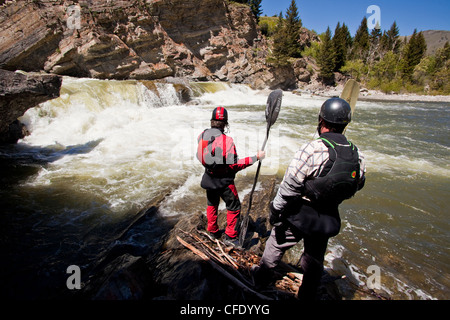 Zwei männliche Wildwasser-Kajakfahrer scout die Wasserfälle am Oldman River, Alberta, Kanada Stockfoto