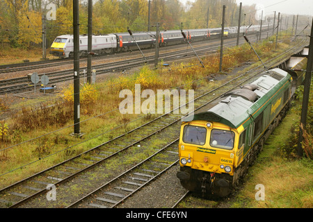 Klasse 66 Diesel Lokomotive 66615 mit Zug der leere Kohlewagen und Class 91 elektrische Lok mit Schnellzug außerhalb von York. Stockfoto