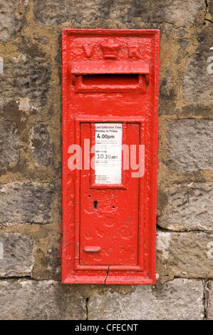 Leuchtend rote ikonischen historischen Wand-viktorianischen VR Post Box in Stein Wand (Nahaufnahme, Ansicht von vorn) - leathley, North Yorkshire, England, UK. Stockfoto