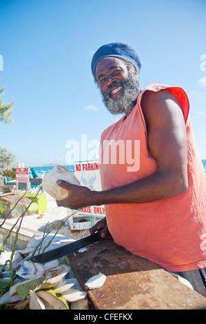 Lächelnd, bärtig, schwarzen Mann mit Hut Kokosnüsse am Orient Beach, Saint-Martin zu verkaufen Stockfoto