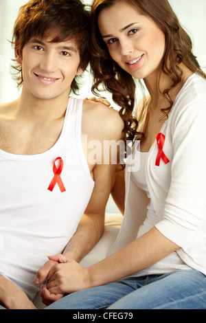 Vertikale Schuss von zarten paar AIDS-Kampagne zu unterstützen und tragen rote Schleifen Stockfoto