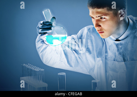 Junge Wissenschaftler eng mit Blick auf leuchtende blaue Flüssigkeit in ein Becherglas gegossen Stockfoto