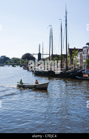 Alte Segelschiffe am Flussufer an einem sonnigen Sommertag in Leiden in den Niederlanden mit Blick auf die Windmühle und Aufhebung-Brücke Stockfoto