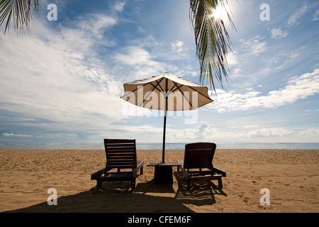 Zwei leere Liegestühle und ein Sonnenschirm am Strand in Bali Stockfoto