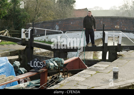 Ein Mann hält ein Seil zu einem schmalen Boot durch Stocker Lock Teil des Grand Union Canal in Rickmansworth Herts UK Stockfoto
