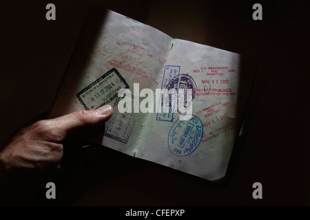 Ein Mann hält einen Reisepass mit internationalen Einwanderung Briefmarken in seiner hand Stockfoto