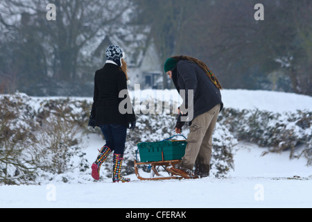 Kaukasischen Jüngling mit Dreadlocks und eine junge Frau mit einem Schlitten im Schnee Stockfoto