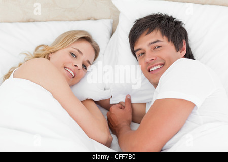 Mann und Frau einander im Bett, beim Nachschlagen und lächelnd Stockfoto