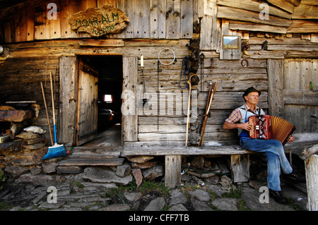 Käser spielt Akkordeon vor seinem Haus Schnals Tal, Alto Adige, Südtirol, Italien Stockfoto