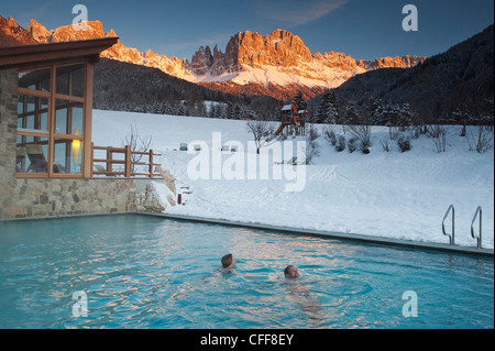 Menschen in einem Pool vor Dolomiten am Abend Tiersertal Tal, Südtirol, Alto Adige, Italien, Europa Stockfoto