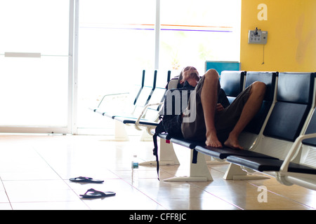 Eine erschöpfte männliche Reisende wartet in einem Flughafen-terminal für seinen Flug nach Ankunft am internationalen Flughafen Manzanillo in Coli Stockfoto