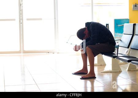 Eine erschöpfte männliche Reisende wartet in einem Flughafen-terminal für seinen Flug nach Ankunft am internationalen Flughafen Manzanillo in Coli Stockfoto