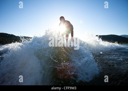 Ein sportlicher Mann Surfen hinter einem Wakeboard-Boot bei Sonnenuntergang in Idaho. Stockfoto