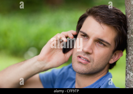 Ernsten jungen Mann wegsehen während des Anrufs mit seinem Handy Stockfoto
