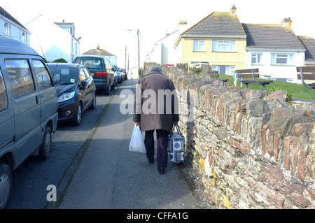 Ein Alter Mann geht auf einem steilen Hügel mit seinen Einkaufsmöglichkeiten in Falmouth, England Stockfoto