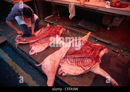 China, Hong Kong, Wanchai, Metzgerei, Metzger zerkleinern Schwein Karkasse Stockfoto